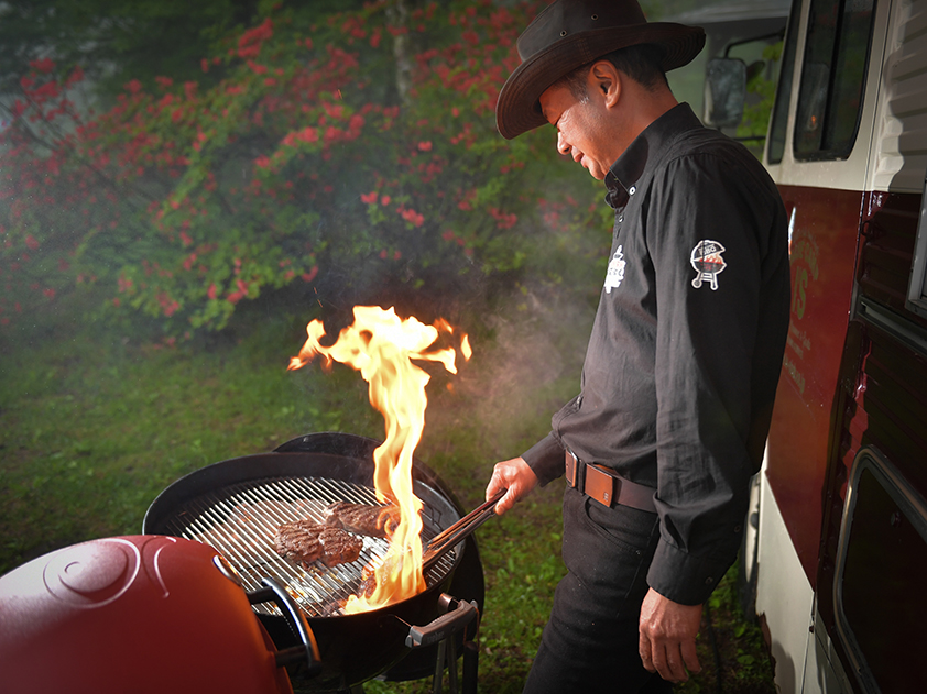 夜の別荘ガーデンでグリルから炎が立ち上がるステーキ